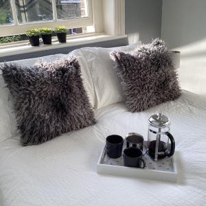a tray with cups and a tea kettle on a bed at Fifty Shades of Gorgeous Greys in London