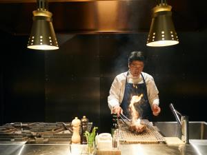 a man in a kitchen preparing food on a stove at YANMAR SUNSET MARINA CLUBHOUSE&HOTEL in Moriyama