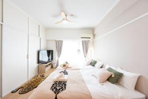 1 dormitorio con 2 camas y TV en Beige, en Tokio
