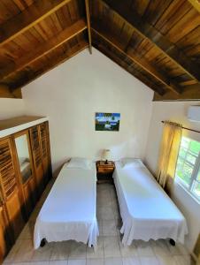 two beds in a room with wooden ceilings at Green's Palace Jamaica in Oracabessa
