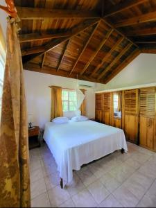 una camera da letto con un grande letto bianco e soffitti in legno di Green's Palace Jamaica a Oracabessa