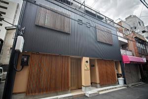 拾野の家 201洋室 في أوساكا: مبنى أسود وأبواب خشبية على شارع