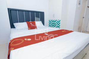 een bed met een rode deken erop bij Redliving Apartemen Grand Sentraland - AT Properti Tower Pink in Karawang