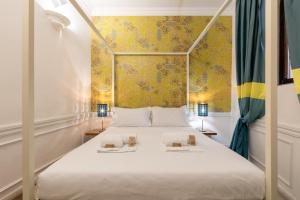 a bedroom with a white bed with a yellow wall at Domus Suite 14 in Rome