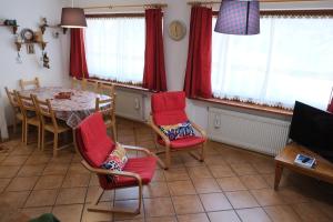 a dining room with a table and red chairs at Al Ruscello in Canazei