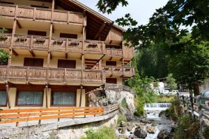 un edificio con balconi e un fiume di fronte ad esso di Al Ruscello a Canazei