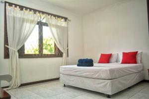 ein Schlafzimmer mit einem Bett mit roten Kissen und einem Fenster in der Unterkunft Kuca Dago IV in Bandung