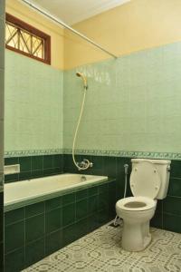 ein grünes Bad mit einem WC und einer Badewanne in der Unterkunft Kuca Dago IV in Bandung