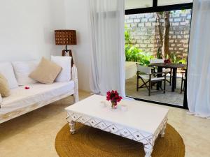 a living room with a white couch and a table at Nyumba Nyekundu in Watamu