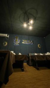 Жемчужина гостиница Балхаш في بالخاش: غرفة مع طاولات وعلامة زون على الحائط
