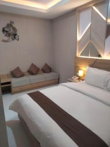 a hotel room with two beds and a couch at Sinergi Hotel & Villa in Sengkaling