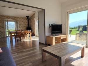 uma sala de estar com um sofá, uma mesa e uma televisão em Villa porte bonheur em Arenthon