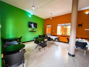 NB MOTEL-KIHIHI في Kihihi: مطعم بجدران خضراء وبرتقالية وطاولات وكراسي