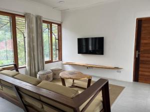 The Cliff 2 Bedroom Beach Apartment في Mazizini: غرفة معيشة مع أريكة وتلفزيون على الحائط