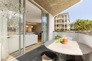 a dining area with a table and glass walls at Bondi Oasis: 2BR + Balcony Bondi Beach in Sydney