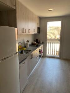 cocina con nevera blanca y ventana grande en Apartamento en el centro, en Igualada