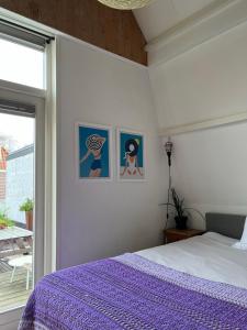 een slaapkamer met een bed met paarse lakens en een raam bij Groenlokaal in Alkmaar