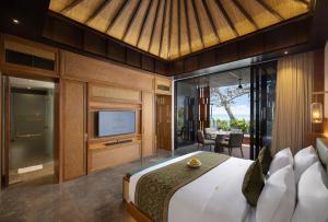 Sumitra Luxury Villas A Pramana Experience في سانور: غرفة نوم بسرير كبير وتلفزيون
