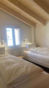 two beds in a room with two windows at am Bärgbach DG in Bettmeralp