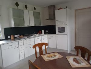 a kitchen with white cabinets and a table and chairs at La Cour Angot in Cormeilles