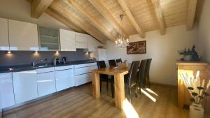 eine Küche mit weißen Schränken und einem Holztisch in der Unterkunft am Bärgbach DG in Bettmeralp