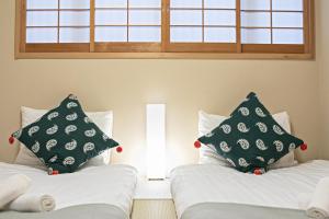 twee bedden met kussens in een kamer bij 拾野の家 202和室 in Osaka