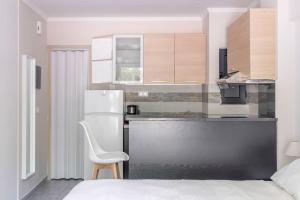 een keuken met een witte stoel en een koelkast bij Voula's Secret Garden Studio in Athene