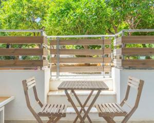 2 sillas de madera y una mesa en el balcón en Voula's Secret Garden Studio, en Atenas