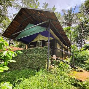 a small house with a thatched roof in a forest at Grassroots Wayanad, Valley-view Tents in Vythiri