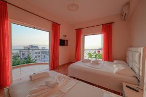 a bedroom with two beds and a large window at Unico ApartHotel in Sarandë