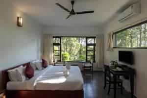 Schlafzimmer mit einem Bett, einem Schreibtisch und einem Fenster in der Unterkunft Avadale Munnar (Stag Groups Not Allowed) in Chinnakanal