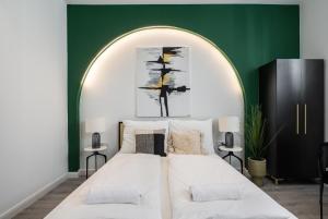 a bedroom with a large white bed with a green wall at R6 - Boutique Apartments, Best Location By BQA in Budapest