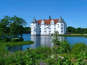 un grand château blanc sur une grande étendue d'eau dans l'établissement Landloft Nedderby, à Husby