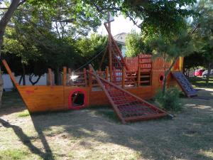 a wooden playground with a slide in a park at Apartments Riva in Pag