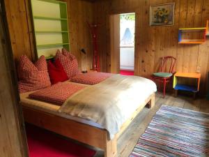 1 dormitorio con cama de madera y almohadas rojas en Villa Alberto - gemütliches Häuschen, en Ötztal-Bahnhof