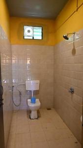 a bathroom with a toilet and a shower and a window at Trippr Gokarna - Beach Hostel in Gokarna