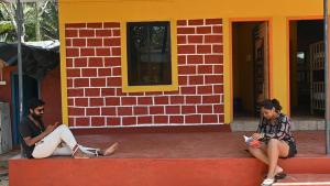 two people sitting on a curb in front of a building at Trippr Gokarna - Beach Hostel in Gokarna