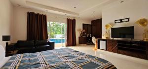 a bedroom with a bed and a tv and a couch at Rawai pool Villa in Phuket Town