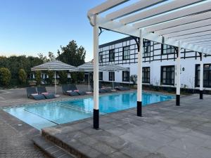 una piscina con sillas y un edificio blanco en ANEW Hotel Hilton Pietermaritzburg en Hilton