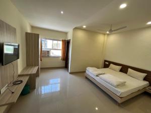 a bedroom with a bed and a flat screen tv at Hotel Pratap Heights in Rānchī