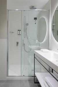 a white bathroom with a shower and a sink at RMH Modena Raffaello in Modena