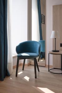 a blue chair in a room with a window at RMH Modena Raffaello in Modena