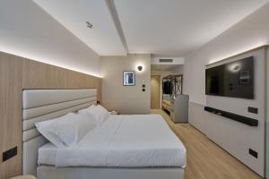 a bedroom with a large white bed and a flat screen tv at RMH Modena Raffaello in Modena