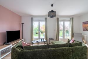 - un salon avec un canapé vert et une télévision dans l'établissement Villa Mana - Sejour entre calme et modernite pour 6, à La Forêt-Fouesnant
