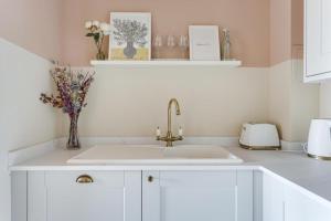 a white kitchen with a sink and flowers on a counter at Large river view room in London