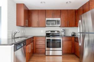 a kitchen with wooden cabinets and stainless steel appliances at Mount Vernon 1BR w Gym Pool nr NoMa Metro WDC-204 in Washington, D.C.