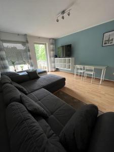 - un salon avec un canapé noir et une table dans l'établissement MG06 Schickes Apartment in Zentrumsnähe, à Mönchengladbach