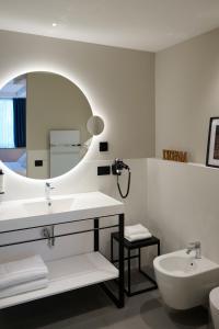 a white bathroom with a sink and a mirror at RMH Modena Raffaello in Modena