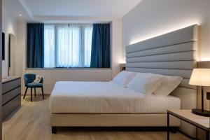 a bedroom with a bed and a chair and a window at RMH Modena Raffaello in Modena