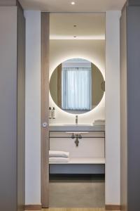a bathroom with a round mirror and a sink at RMH Modena Raffaello in Modena